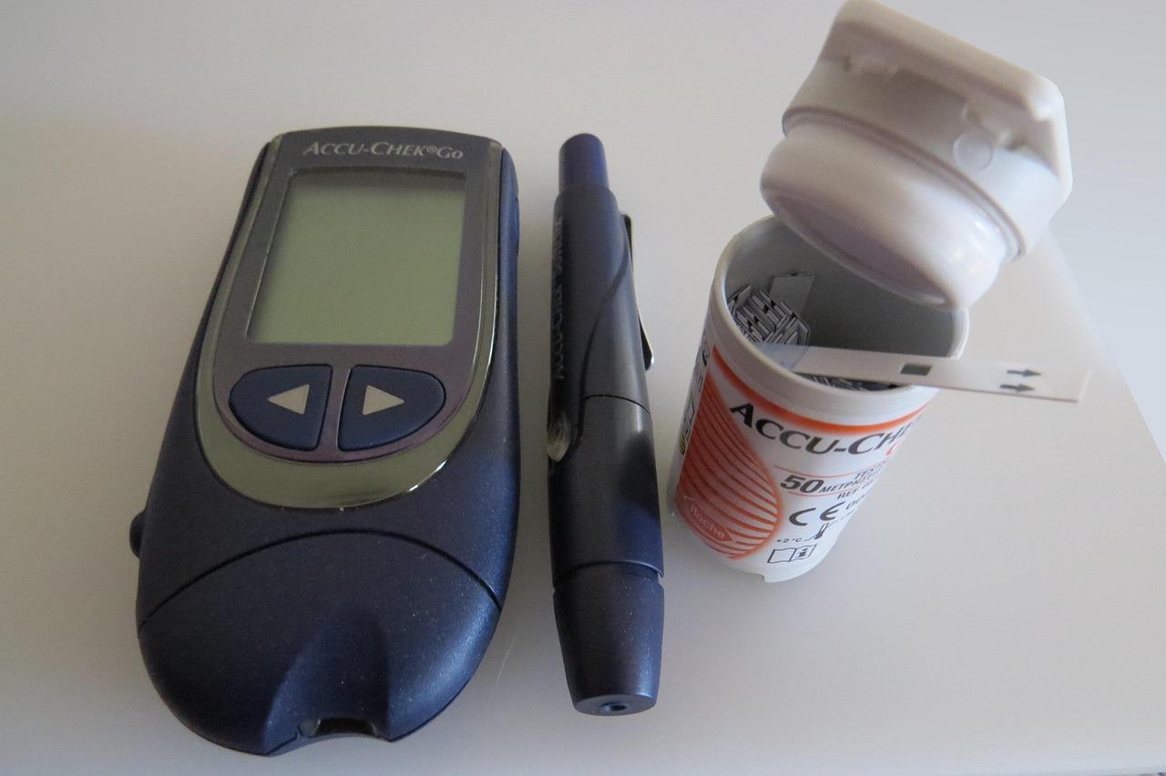 A glucometer kit with test strips and lancing device placed on a wooden desk