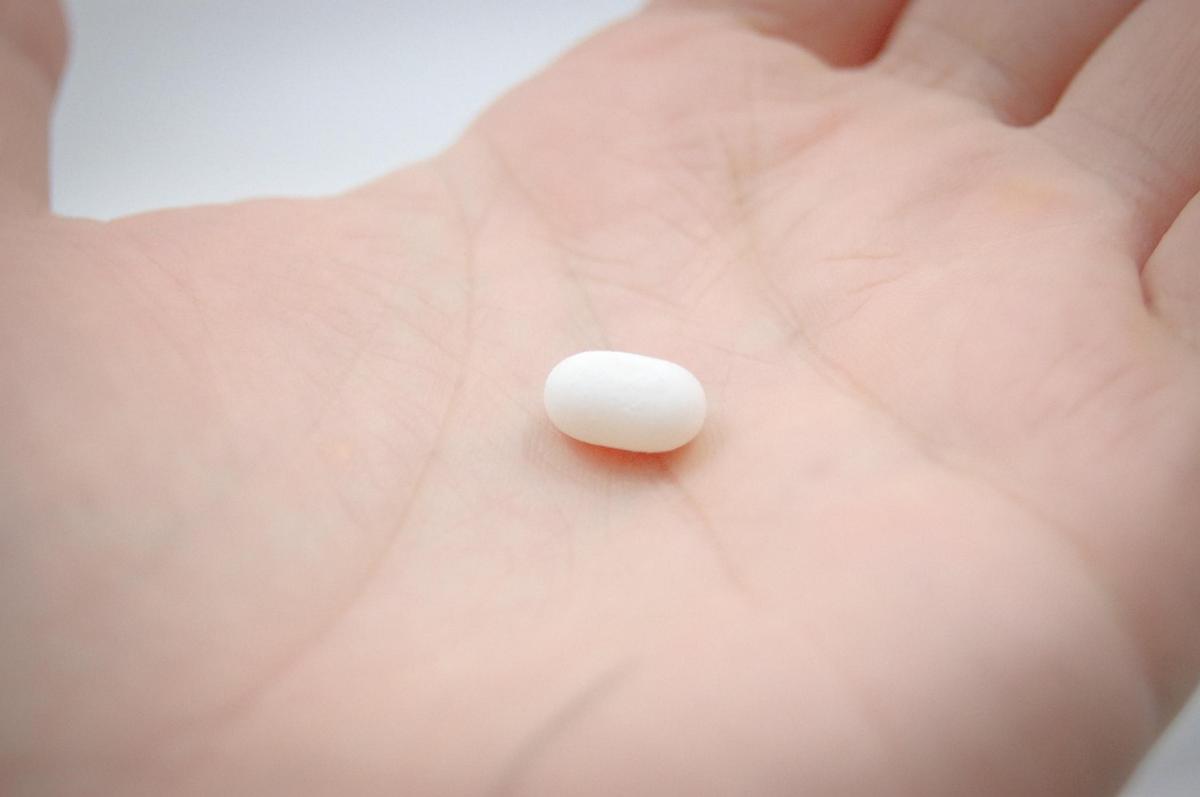 A blister pack of Metformin tablets sitting next to a glass of water on a table