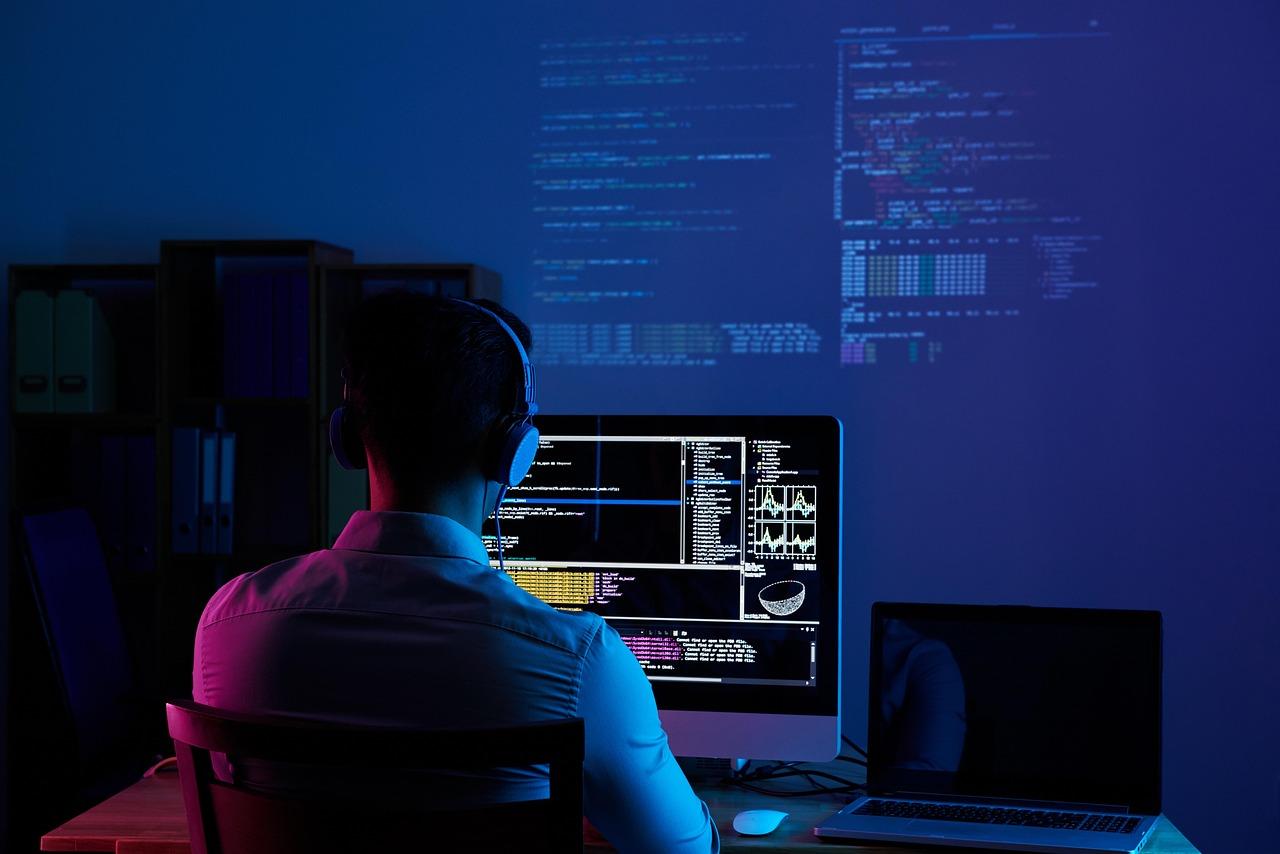 An office worker working late at night in front of illuminated computer screens