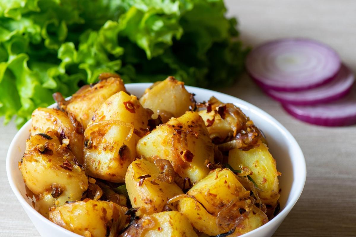 A dish of cooked cauliflower and potato sabzi garnished with fresh cilantro and spices